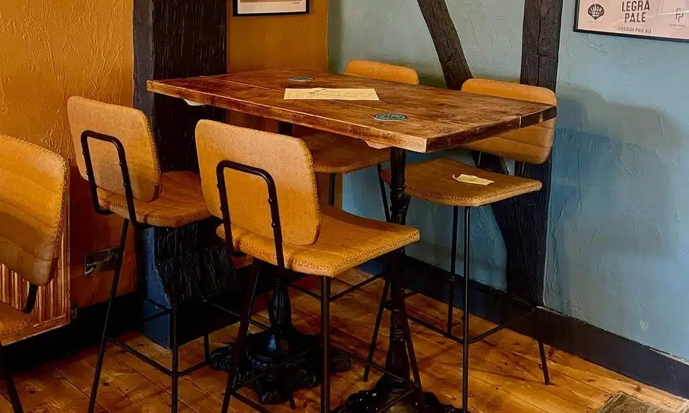 Solid oak restaurant table tops with black pub-style bases and upholstered bar stools at Legra Tap & Kitchen.
