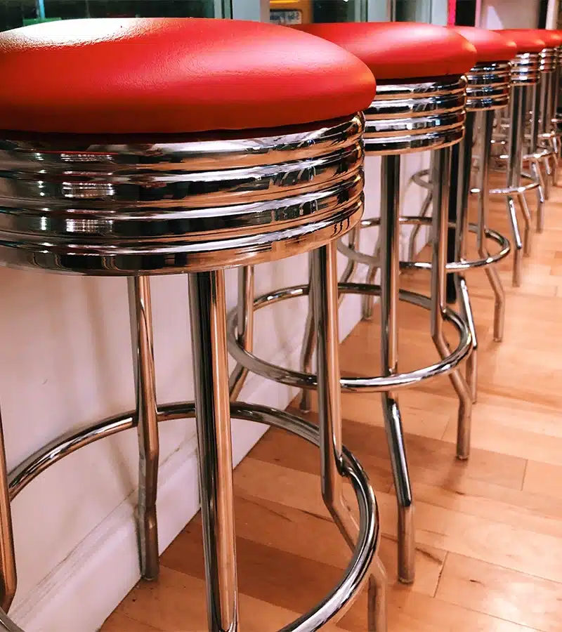 Retro American diner stool next to a chrome ribbed edge table in a classic 50s-style setting
