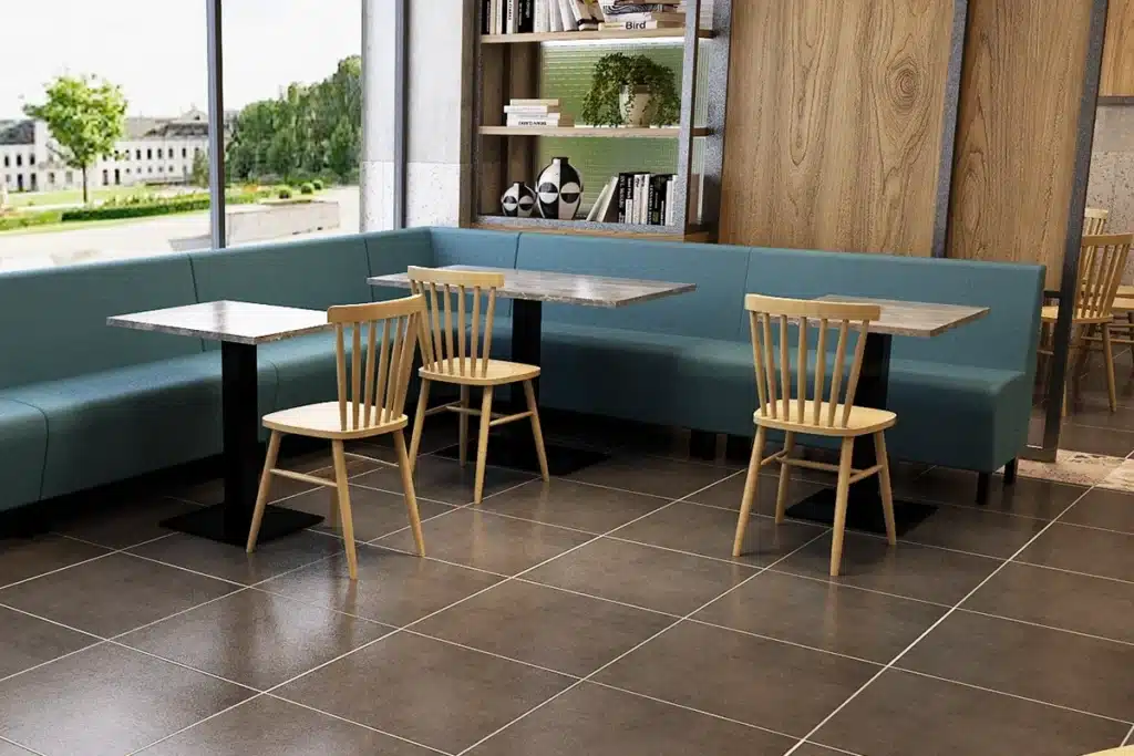 Compact corner booth seating run against a window with small dining tables and chairs opposite, showing a space-saving restaurant layout