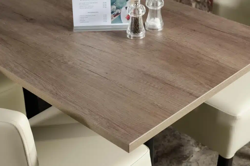 Distressed oak laminate table top with two contract chairs positioned opposite in a restaurant setting.